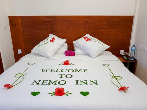 a welcome to nino inn sign on a bed at Nemo Inn in Omadhoo