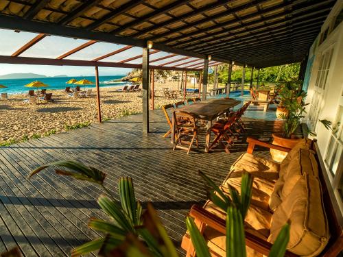 a deck with a table and chairs on the beach at Buzios Espiritualidade Hotel in Búzios
