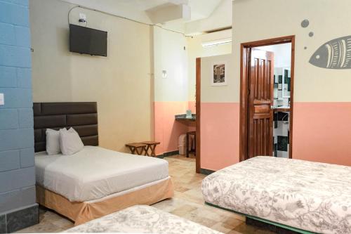 a hotel room with two beds and a television at Casa Palma Hotel in Playa del Carmen