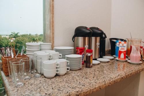 a counter with cups and plates and a coffee maker at SAMIR HOTEL COMFORT in Porto Velho