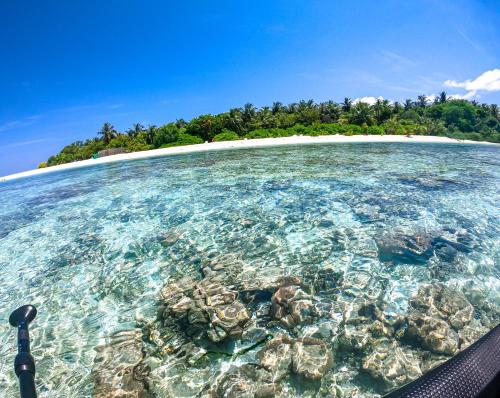 an island in the ocean with a boat in the water at Nemo Inn in Omadhoo