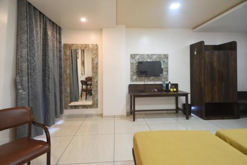 a room with a bed and a desk and a television at ATITHI INN in Boisar