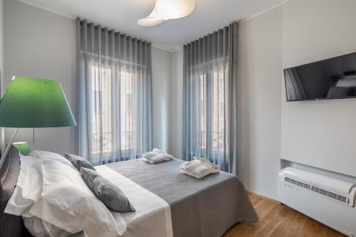 a bedroom with a bed with a green lamp and windows at 30Cavour luxury suites in Pavia