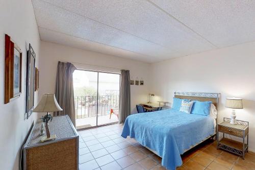 Un dormitorio con una cama azul y una ventana en Ventura Condominiums #204 en South Padre Island