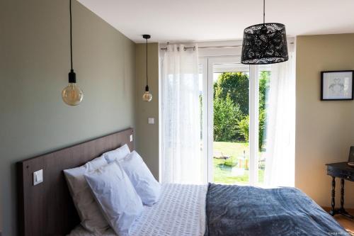 - une chambre avec un lit, une fenêtre et des lampes pendant dans l'établissement Aux Bonheurs du lac, à Gérardmer