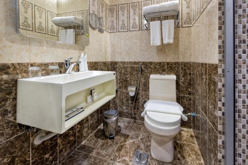 a bathroom with a white toilet and a sink at Sansa Hotel in Jeddah