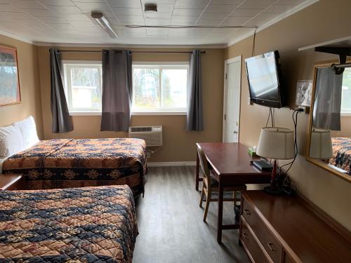 a hotel room with two beds and a desk and a television at Village Inn & Suites - Sudbury in Lively