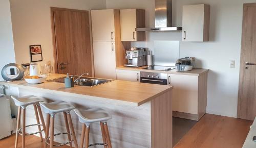 a kitchen with a sink and a counter with stools at Appart Hotel Nivelles in Nivelles