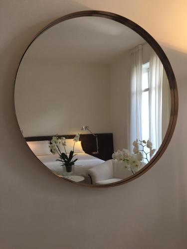 a mirror reflecting a living room with a couch and flowers at Collalto24 in Treviso