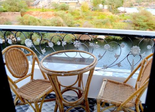 two chairs and a glass table on a balcony at Onaty Ka Guest House in Aswan