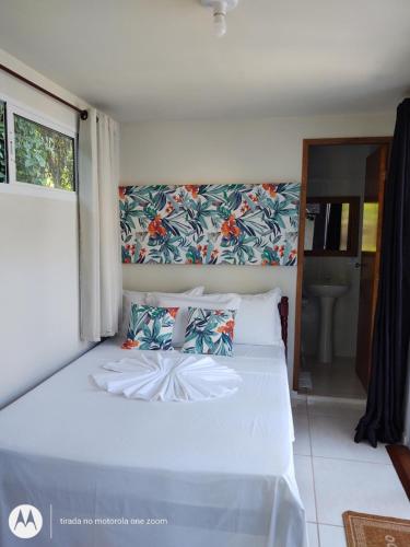 1 cama con sábanas blancas y almohadas en una habitación en Nalu Guest House en Ubatuba