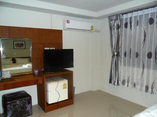 a living room with a tv and a desk with a computer at The City House in Krabi town