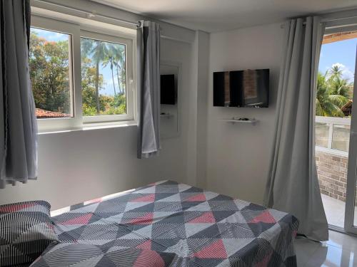 a bedroom with a bed and two windows at Makaiba Residence Flat dr Artur Licio in Porto De Galinhas