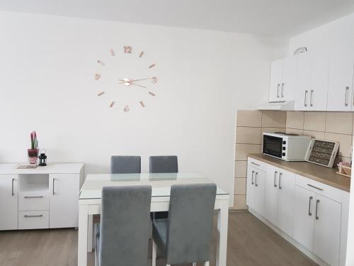 a kitchen with a table and a clock on the wall at Apartment GEA 18 in Novi Sad