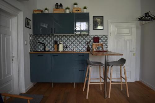 een keuken met blauwe kasten en een tafel en stoelen bij Atelier Foto Lipowa - Apartamenty in Nałęczów