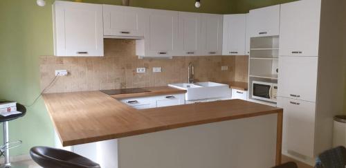 une cuisine avec des armoires blanches et un comptoir en bois dans l'établissement Appt 75m2 terrasse 12m2, à Tourbes