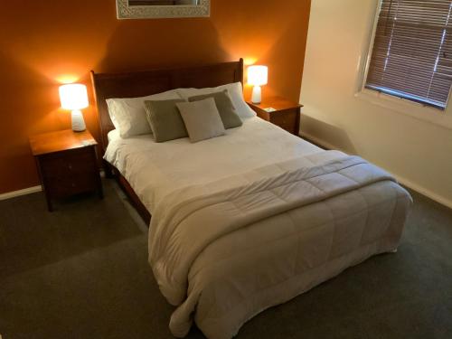 a bedroom with a large white bed with two lamps at Oats Cottage in Hahndorf