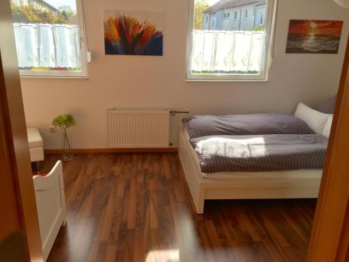 a small room with a bed and two windows at Ferienwohnung Windhaus in Dortmund