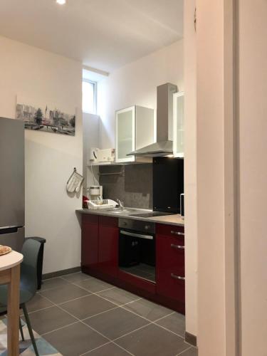 a kitchen with red cabinets and a black stove at NOUVEAU : Le puits de Sarlat in Sarlat-la-Canéda