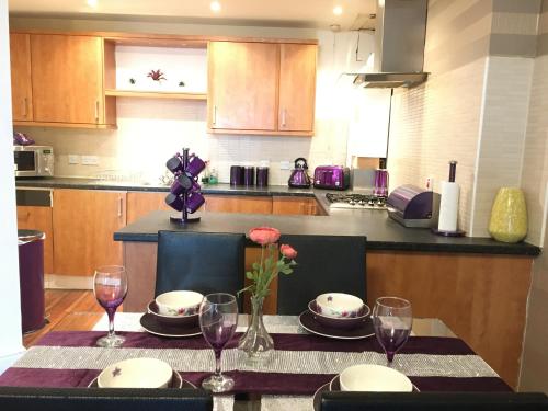 a kitchen with a table with plates and wine glasses at Cozy Nights - Cambuslang 1/64 in Glasgow