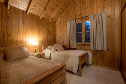 a bedroom with two beds and a window at Apart Hotel Naum in San Martín de los Andes