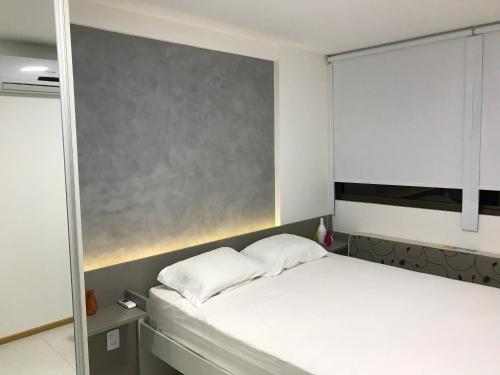 1 dormitorio con cama blanca y pizarra en Charmoso Flat Nui Supreme - Térreo, en Porto de Galinhas