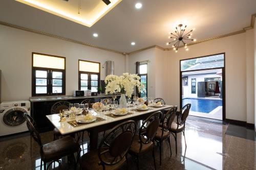 a dining room with a long table and chairs at Lanna Kamin Pool Villa Airport in Chiang Mai