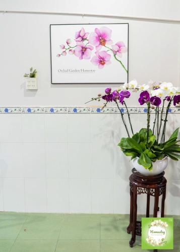 a vase of flowers on a table in a room at Can Tho Orchid Garden Homestay in Can Tho