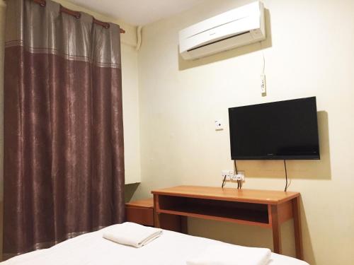 a bedroom with a bed and a tv and a desk at HK Inn Hua Kiew Inn in Miri