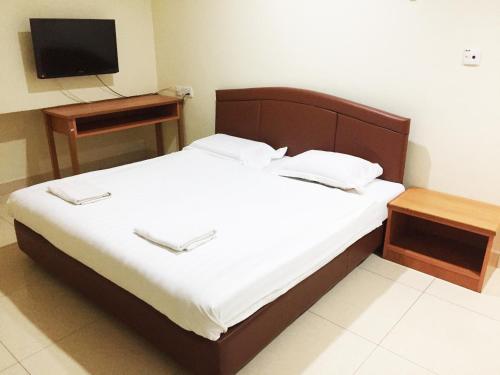 a bedroom with a bed with a television and a table at HK Inn Hua Kiew Inn in Miri