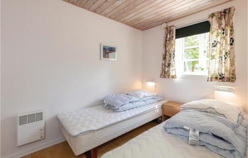 two beds in a room with a window at Skagenhuset Lejl 1 in Allinge