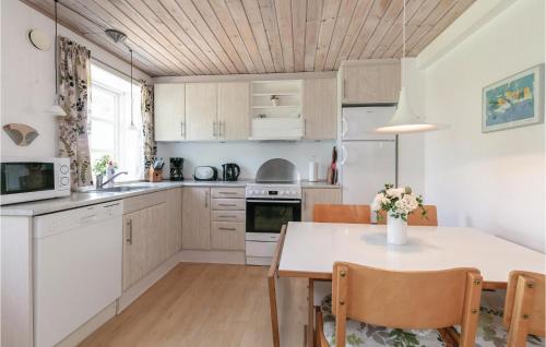 a kitchen with white cabinets and a table with chairs at Skagenhuset Lejl 1 in Allinge