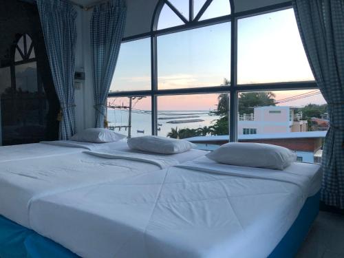 two beds in a room with a large window at ฟ้าทะลายโจรรีสอร์ท in Prachuap Khiri Khan