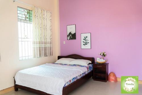 a bedroom with a bed and a purple wall at Can Tho Orchid Garden Homestay in Can Tho
