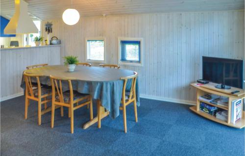 a dining room with a table and chairs and a tv at Holiday Home Sommerbyen Nyborg Ii in Nyborg