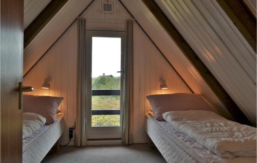 Bjerregårdにある3 Bedroom Amazing Home In Hvide Sandeのベッド2台と窓が備わる屋根裏部屋です。