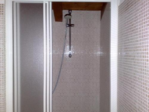 a shower in a bathroom with white tiled walls at Villa Stefy in Dervio