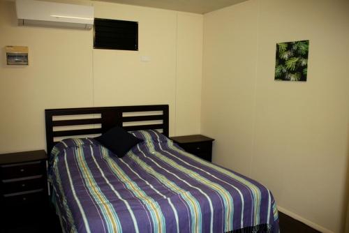 1 dormitorio con 1 cama con manta a rayas en Spring Homestead, en Howard Springs