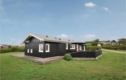 a black house with a porch and a grass field at Three-Bedroom Holiday Home In Vinderup in Vinderup