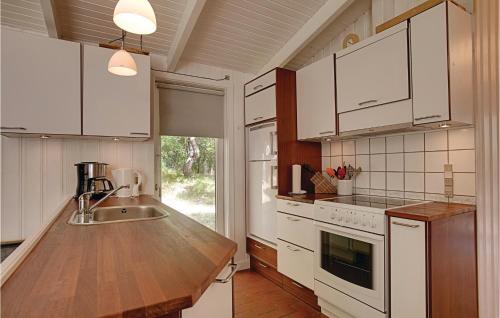 a kitchen with white cabinets and a wooden counter top at Holiday Home Brogårdsvejen Nexø X in Bedegård