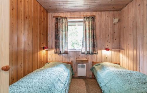BalkeにあるBeautiful Home In Nex With Kitchenのウッドウォールと窓が備わるドミトリールームのベッド2台分です。