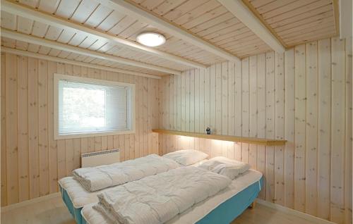 a bedroom with a bed in a room with wooden walls at Cozy Home In Nex With Sauna in Snogebæk