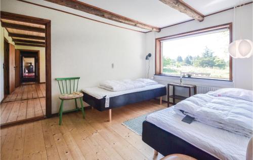 a bedroom with two beds and a chair and a window at Three-Bedroom Holiday Home In Frostrup in Frøstrup