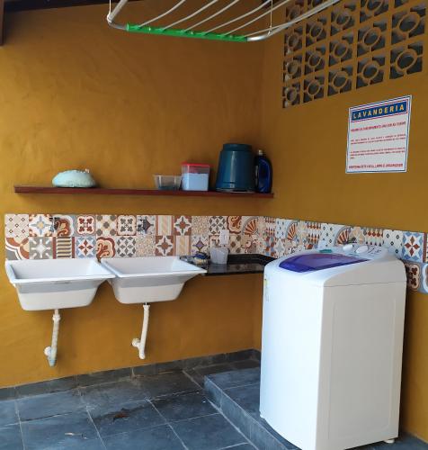 a bathroom with two sinks and a refrigerator at Chalé Pousada da Aldeia in Boicucanga
