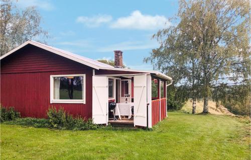 a red and white shed on a grass field at 2 Bedroom Amazing Home In Hedekas in Hedekas