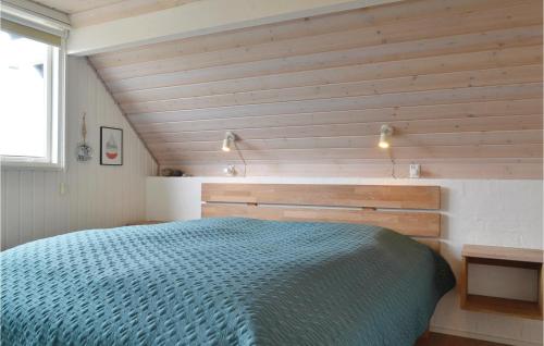 a bedroom with a blue bed and wooden walls at Beautiful Home In Hvide Sande With Kitchen in Havrvig