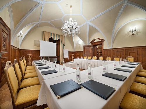 a conference room with tables and chairs and a chandelier at EA Zamecky Hotel Hruba Skala in Hrubá Skála