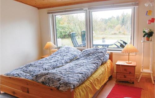 a bed in a room with a large window at Beautiful Home In Roslev With 2 Bedrooms in Glyngøre