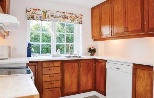 a kitchen with wooden cabinets and a window at Two-Bedroom Holiday Home In Hornbak in Hornbæk