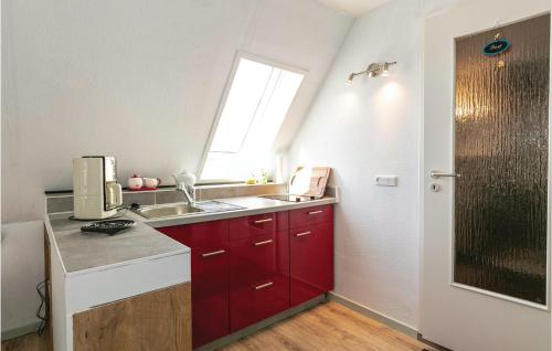 een kleine keuken met rode kasten en een raam bij Awesome Apartment In Nex With Kitchen in Neksø